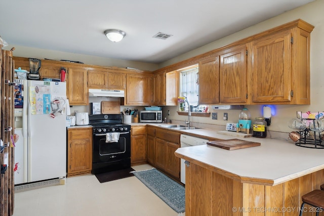 kitchen with a breakfast bar, sink, white appliances, and kitchen peninsula