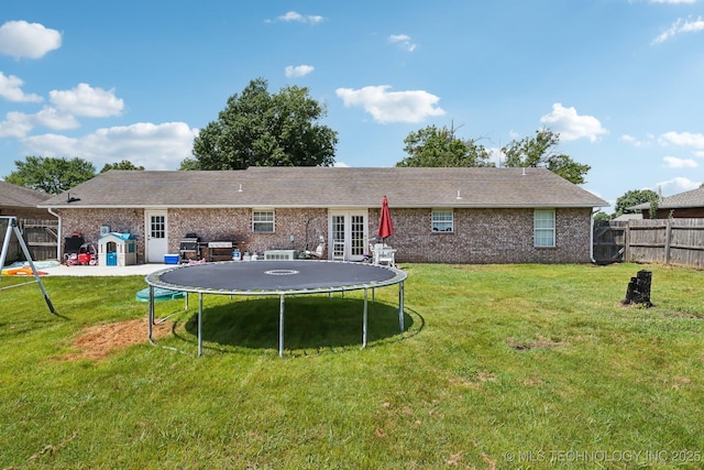 back of property featuring a yard, a trampoline, and french doors