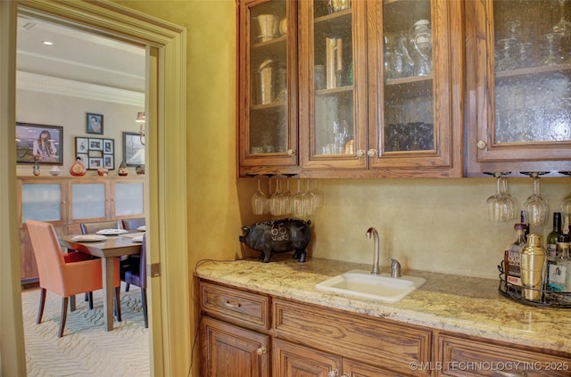 kitchen featuring light stone counters, sink, and crown molding