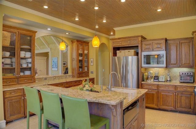 kitchen with appliances with stainless steel finishes, a breakfast bar, a center island with sink, and decorative light fixtures