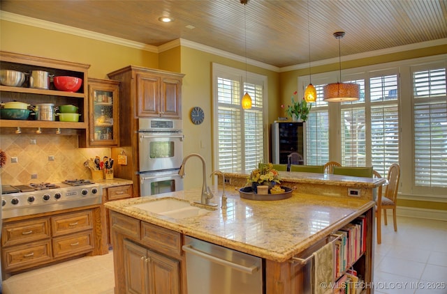 kitchen with sink, crown molding, appliances with stainless steel finishes, hanging light fixtures, and an island with sink