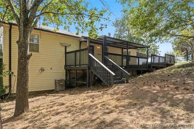 rear view of property with a wooden deck and cooling unit