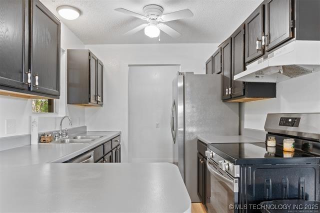 kitchen with electric stove, dark brown cabinetry, sink, and a textured ceiling