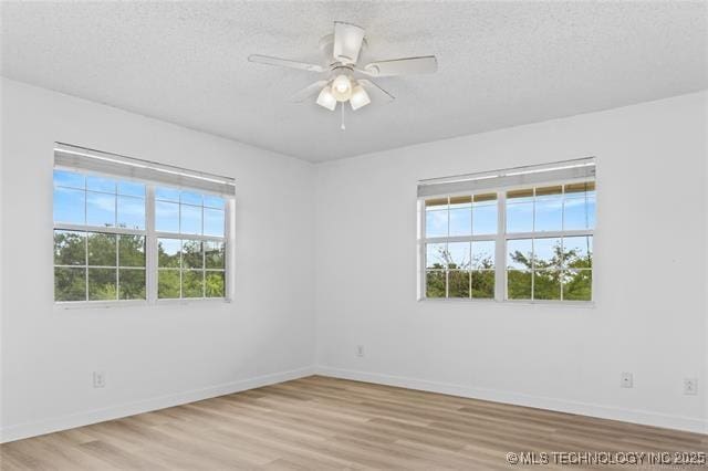 unfurnished room featuring light hardwood / wood-style flooring, a wealth of natural light, and a textured ceiling