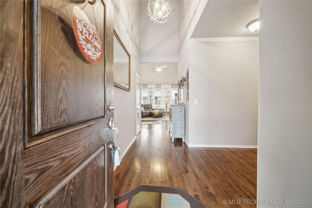 entrance foyer with a towering ceiling, dark wood-type flooring, ornamental molding, and ceiling fan