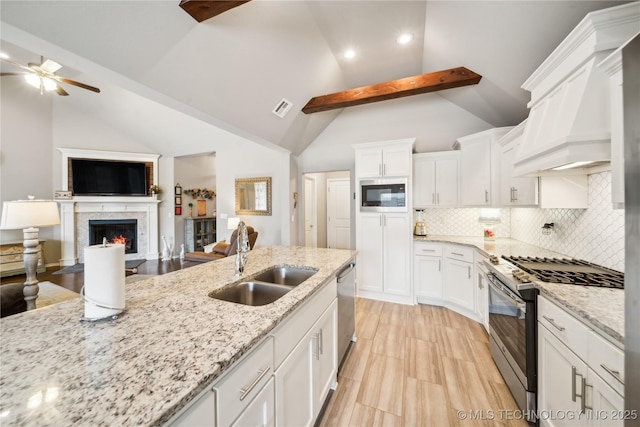 kitchen with appliances with stainless steel finishes, sink, white cabinets, custom exhaust hood, and light stone countertops