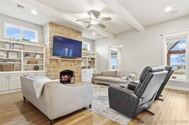 living room with beamed ceiling, plenty of natural light, a fireplace, and light hardwood / wood-style floors