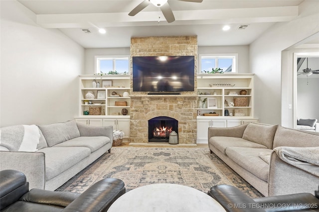 living room with ceiling fan, a wealth of natural light, a fireplace, and beamed ceiling