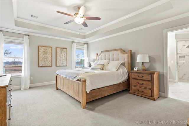 carpeted bedroom featuring ensuite bath, ornamental molding, and a tray ceiling