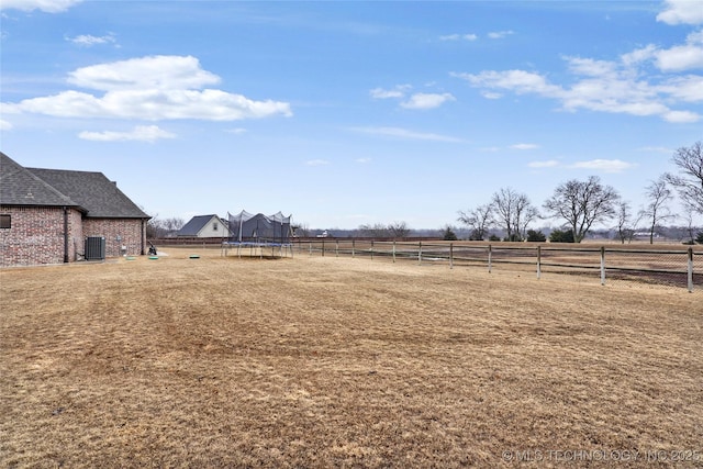 view of yard with a rural view, a trampoline, and cooling unit