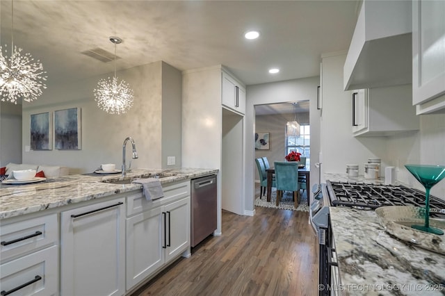 kitchen featuring appliances with stainless steel finishes, white cabinets, an inviting chandelier, and wall chimney exhaust hood