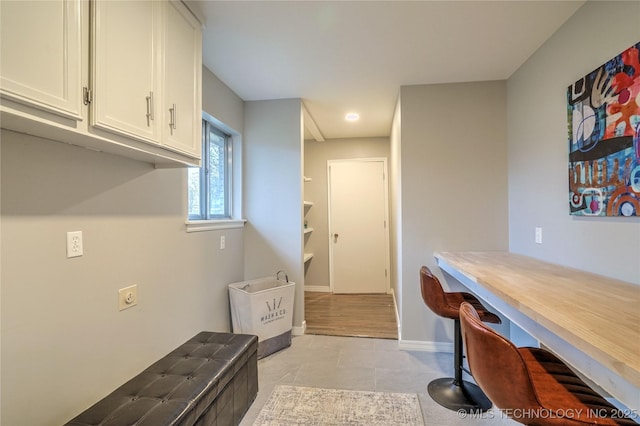 interior space with light tile patterned floors, built in desk, and white cabinets