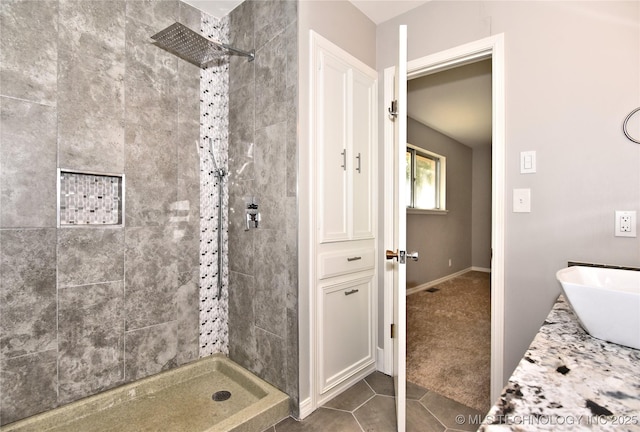 bathroom featuring tile patterned flooring, tiled shower, and sink