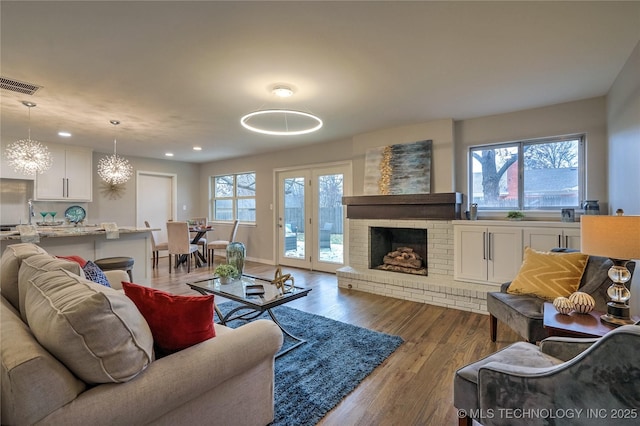 living room with dark hardwood / wood-style floors, a chandelier, and a fireplace