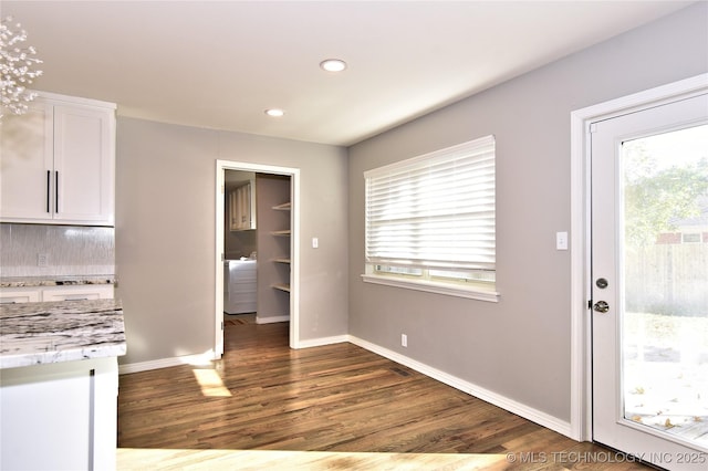 unfurnished dining area with dark wood-type flooring