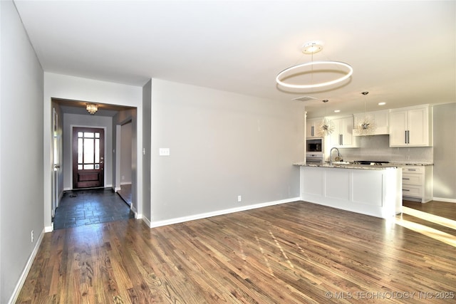 kitchen featuring built in microwave, white cabinetry, hanging light fixtures, dark hardwood / wood-style floors, and backsplash