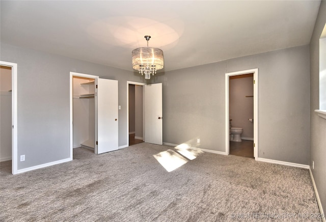 unfurnished bedroom with connected bathroom, a notable chandelier, and carpet