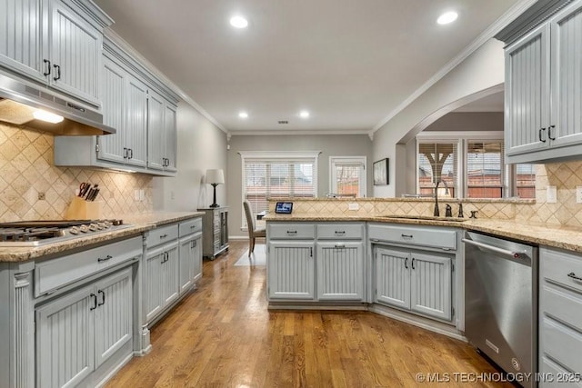 kitchen with gray cabinets, appliances with stainless steel finishes, light wood-style floors, ornamental molding, and under cabinet range hood