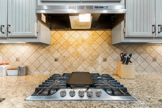 kitchen featuring stainless steel gas cooktop, under cabinet range hood, gray cabinetry, and light stone countertops