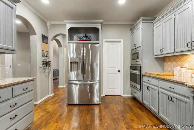 kitchen featuring crown molding, gray cabinetry, stainless steel appliances, light stone countertops, and decorative backsplash