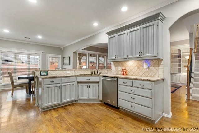 kitchen with a sink, a peninsula, tasteful backsplash, arched walkways, and dishwasher