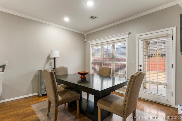 dining space featuring baseboards, visible vents, wood finished floors, crown molding, and recessed lighting