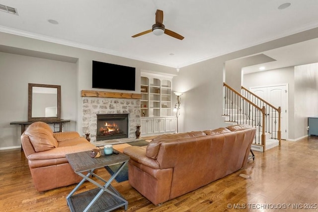 living area with stairway, a fireplace, visible vents, and wood finished floors