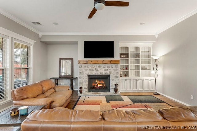 living room featuring hardwood / wood-style flooring, crown molding, ceiling fan, and a fireplace