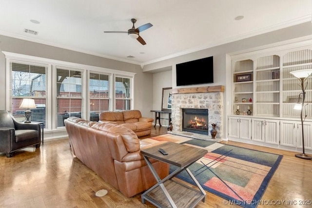 living room featuring crown molding, ceiling fan, a fireplace, and light hardwood / wood-style flooring