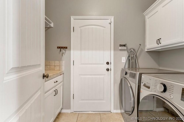 washroom featuring light tile patterned floors, baseboards, cabinet space, and washer and clothes dryer