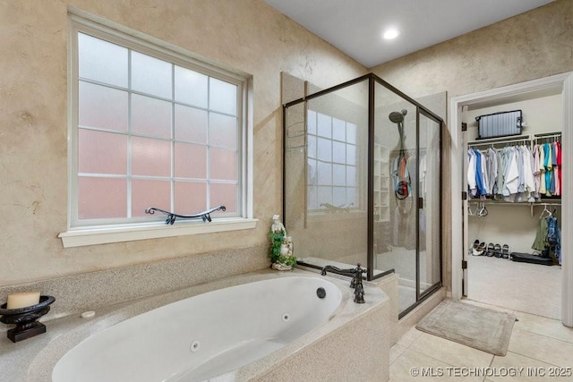 full bathroom with a jetted tub, a stall shower, tile patterned flooring, and a spacious closet