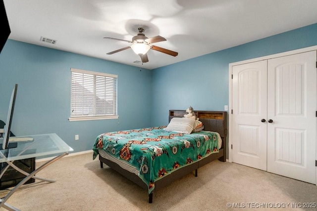 bedroom featuring light colored carpet, ceiling fan, and a closet