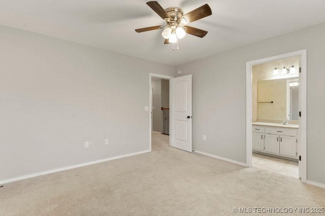 unfurnished bedroom with ceiling fan, connected bathroom, light colored carpet, a sink, and baseboards