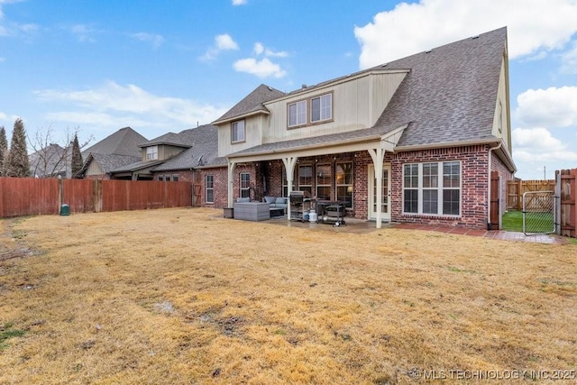 back of house with brick siding, a yard, a patio, outdoor lounge area, and a fenced backyard