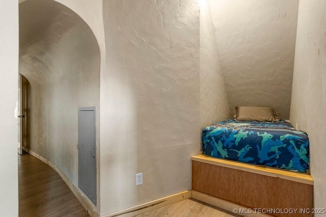 unfurnished bedroom featuring light wood-style floors and arched walkways