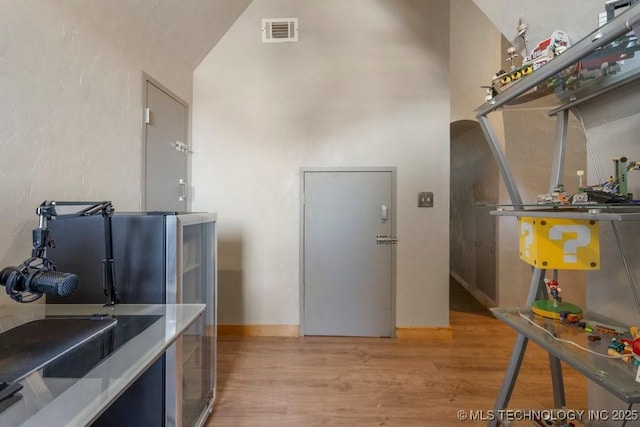 kitchen with light countertops, light wood-type flooring, visible vents, and a towering ceiling