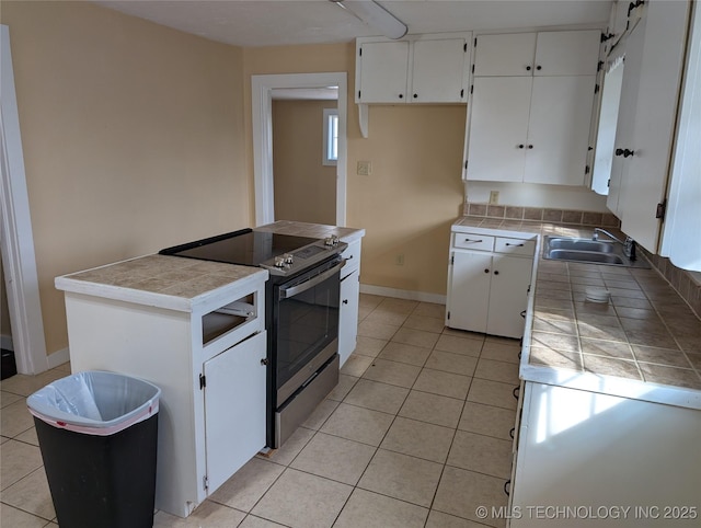 kitchen featuring sink, white cabinets, tile counters, light tile patterned floors, and stainless steel electric range