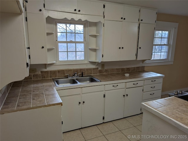 kitchen featuring tile countertops, sink, and white cabinets