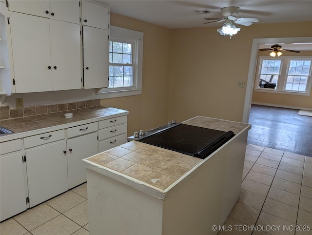 kitchen with tile countertops, light tile patterned floors, and white cabinets