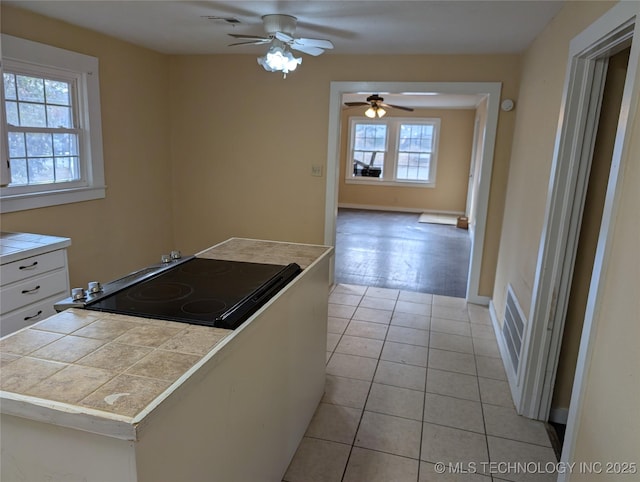 kitchen with black electric cooktop, ceiling fan, light tile patterned floors, and white cabinets