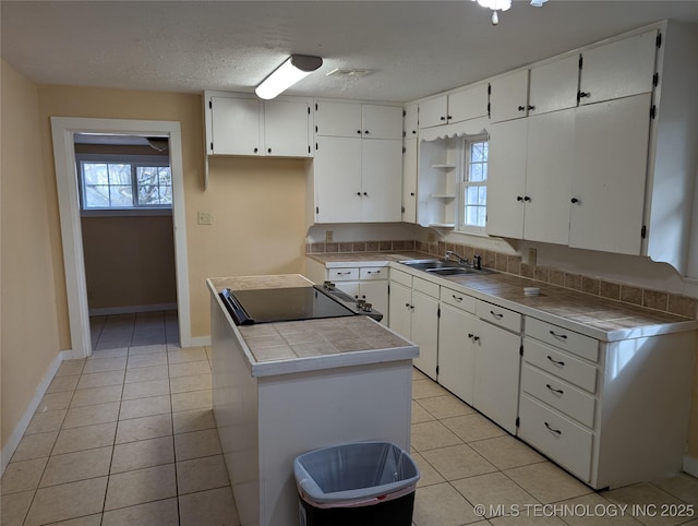 kitchen featuring light tile patterned floors, tile counters, sink, and white cabinets