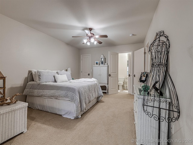 carpeted bedroom with ensuite bathroom and ceiling fan