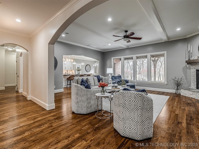 living room featuring ceiling fan, ornamental molding, a fireplace, and dark hardwood / wood-style flooring