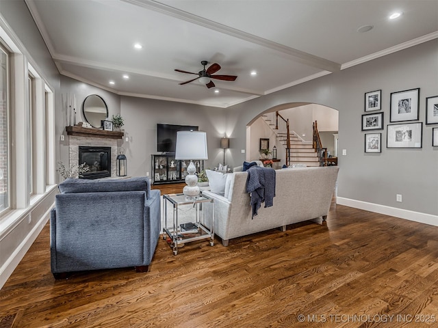 living room with dark hardwood / wood-style flooring, crown molding, and ceiling fan