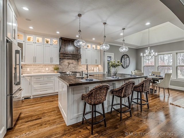 kitchen with white cabinetry, custom range hood, and high end fridge