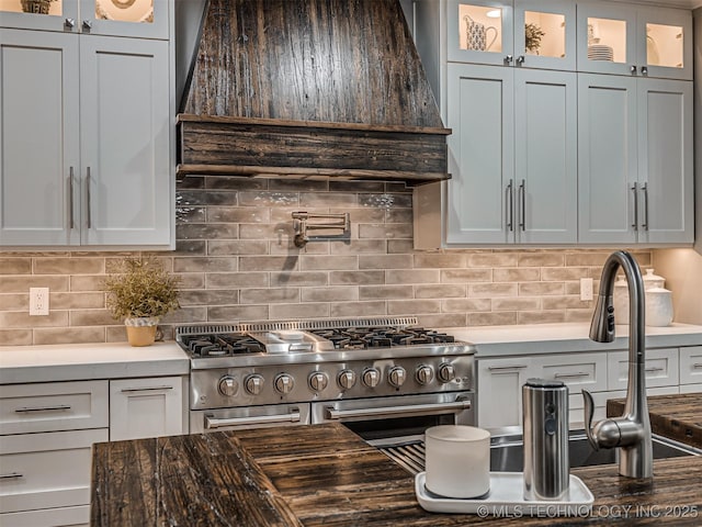 kitchen with custom exhaust hood, double oven range, and tasteful backsplash