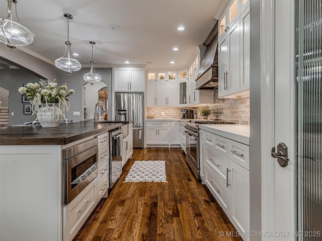 kitchen featuring premium range hood, white cabinetry, stainless steel appliances, dark hardwood / wood-style floors, and decorative light fixtures