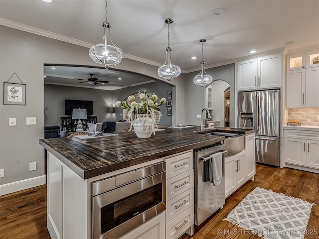 kitchen featuring stainless steel appliances, hanging light fixtures, a center island with sink, and white cabinets