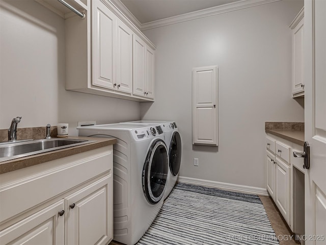 washroom with cabinets, crown molding, washer and dryer, and sink