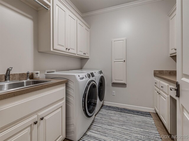 laundry room with cabinets, ornamental molding, sink, and washer and dryer